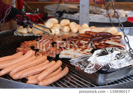 An assortment of sausages and meats on a large outdoor grill 138696017