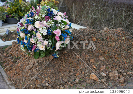 Fresh grave mound with flowers in cemetery burial 138696043