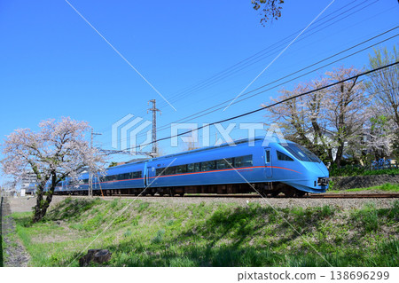 一列天藍色的小田急60000系列MSE浪漫列車在藍天下行駛，周圍環繞著櫻花。 138696299