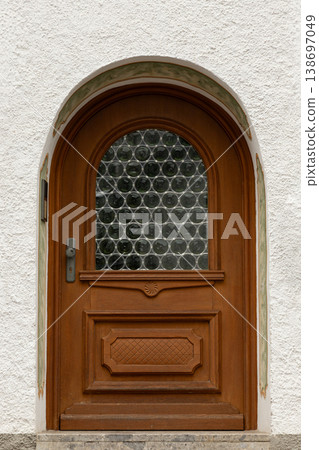 Arched wooden door with circular glass block window Arched wooden door with circular glass block window 138697049