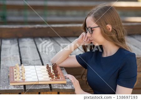 Caucasian woman playing chess outdoors.  138697193