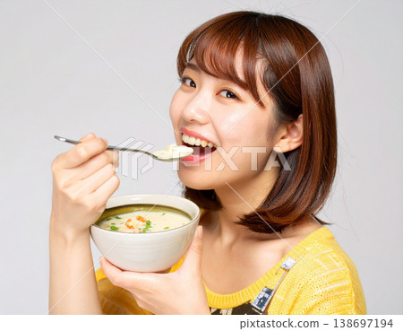 一位年輕女子一邊喝湯一邊微笑；健康飲食；生活方式 138697194
