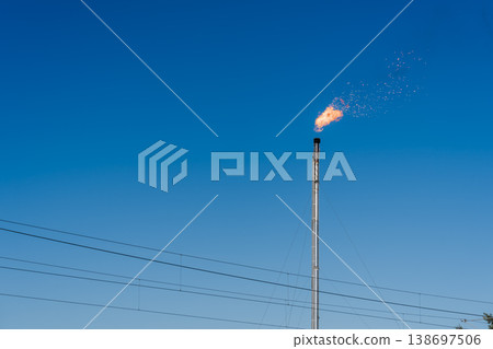藍天下，煉油廠的火炬塔和電線燃燒著火焰。 138697506