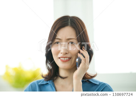 一位中年婦女正在用智慧型手機通話。 一位中年婦女正在用智慧型手機通話。 138697724