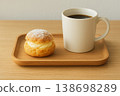 A cream puff and coffee placed on the table 138698289
