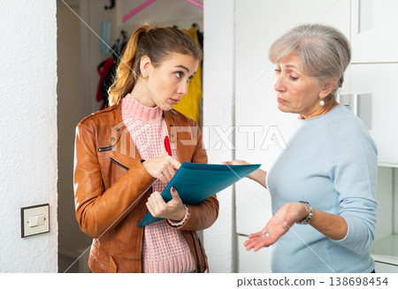 Frustrated senior woman talking to female debt collector at home 138698454