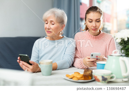 Senior woman and her granddaughter using smartphones at home 138698487