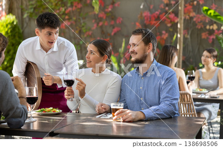 Waiter talking to restaurant guests - taking orders for food and drinks Waiter talking to restaurant guests - taking orders for food and drinks 138698506