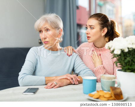 Adult daughter calming upset mother after quarrel at table 138698513