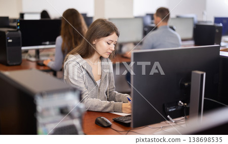 Young woman taking notes while working at computer 138698535