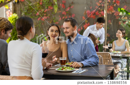 Meeting of two married couples in cozy open-air restaurant Meeting of two married couples in cozy open-air restaurant 138698556