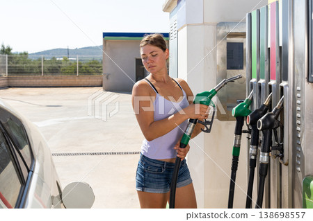 Woman filling up tank of her car with gasoline 138698557