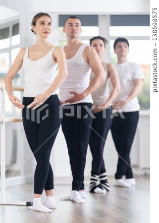 Group of dancers stand in fifth position at barre 138698575