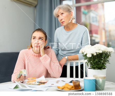 Frustrated girl and elderly woman counting cash at table at home 138698588