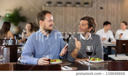 Couple men eating and talking in restaurant 138698608