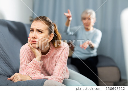 Elderly mother reprimanding frustrated girl sitting on sofa Elderly mother reprimanding frustrated girl sitting on sofa 138698612