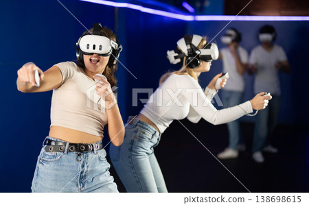 Two girls wearing virtual reality glasses participate in game with opponents Two girls wearing virtual reality glasses participate in game with opponents 138698615