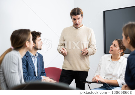 Positive successful man standing near interactive board and communicating with group of adult students at seminar in advanced training Positive successful man standing near interactive board and communicating with group of adult students at seminar in advanced training 138698668
