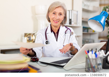 Friendly female doctor hands out prescription to patient in office 138698672