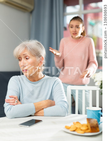 Offended aged mothe listening to reproaches from adult daughter at table Offended aged mothe listening to reproaches from adult daughter at table 138698693