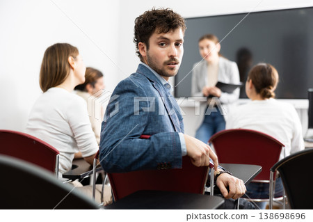 Young smiling man attending lecture in university 138698696