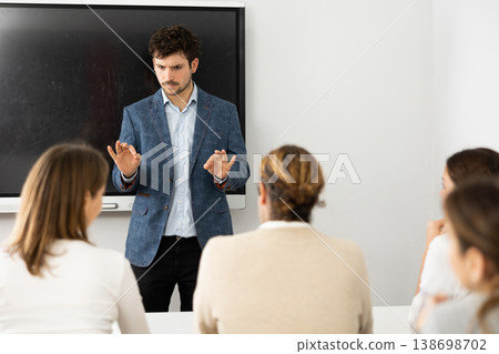 Young male professor explaining subject to classroom full of students 138698702