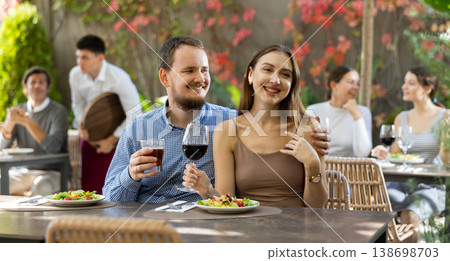 Portrait of loving couple with glasses of wine at table in an open-air restaurant Portrait of loving couple with glasses of wine at table in an open-air restaurant 138698703