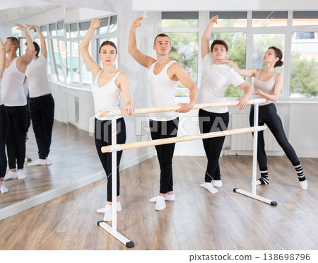 Group of ballet enthusiasts practicing at barre with experienced ballerina Group of ballet enthusiasts practicing at barre with experienced ballerina 138698796
