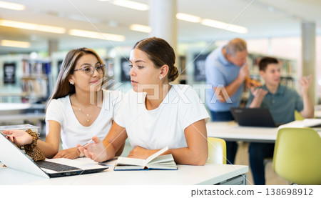 Two positive ladies behave loudly while studying in the library and using computer Two positive ladies behave loudly while studying in the library and using computer 138698912