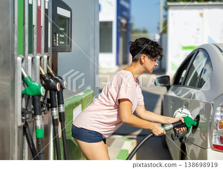 Smiling woman refueling her car in gas station Smiling woman refueling her car in gas station 138698919