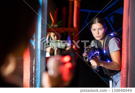 Girl running and dodging while playing lasertag Girl running and dodging while playing lasertag 138698949