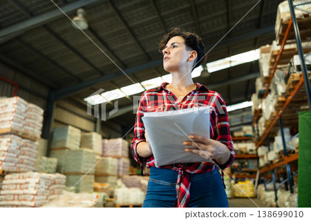 Female storekeeper checks presence of goods in the building materials warehouse Female storekeeper checks presence of goods in the building materials warehouse 138699010