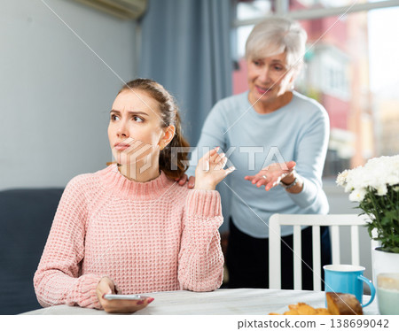 Offended young woman listening to reproaches from mother at table 138699042