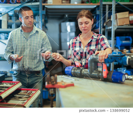 Man and woman assembling plumbing fixture in workshop Man and woman assembling plumbing fixture in workshop 138699052