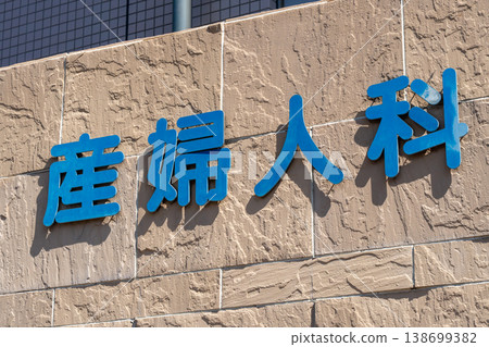 A sign with blue three-dimensional lettering installed on the exterior wall of the obstetrics and gynecology clinic. 138699382