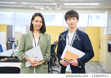 Japanese male and female system engineers chatting and smiling in the office of a foreign-owned IT company. Japanese male and female system engineers chatting and smiling in the office of a foreign-owned IT company. 138699413