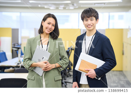 Japanese male and female system engineers chatting and smiling in the office of a foreign-owned IT company. Japanese male and female system engineers chatting and smiling in the office of a foreign-owned IT company. 138699415