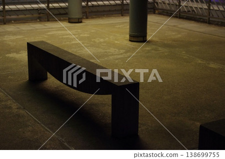 A concrete bench in a park at night, illuminated by streetlights. 138699755