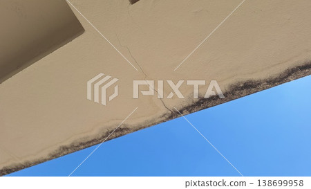 A close-up shot of a damaged concrete ceiling showing a long crack and dark water leakage stains. A close-up shot of a damaged concrete ceiling showing a long crack and dark water leakage stains. 138699958