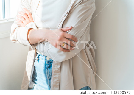 A woman stands by the window in her house, arms crossed, lost in thought. A woman stands by the window in her house, arms crossed, lost in thought. 138700572