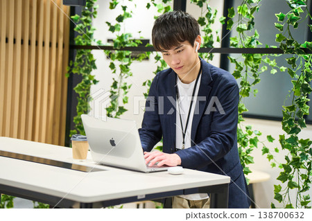 一位來自外資公司的年輕男性系統工程師在綠樹環繞的辦公室裡,站在辦公桌前專心處理電腦工作。 一位來自外資公司的年輕男性系統工程師在綠樹環繞的辦公室裡,站在辦公桌前專心處理電腦工作。 138700632