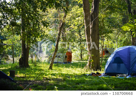 Forest tents, hanging robes and shaded paths create a clear retreat backdrop. The natural scene suits meditation and religion content. 138700668