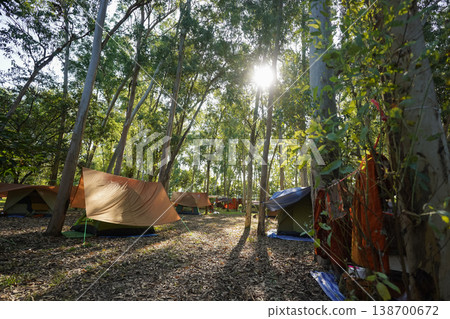 Forest tents, hanging robes and shaded paths create a clear retreat backdrop. The natural scene suits meditation and religion content. 138700672