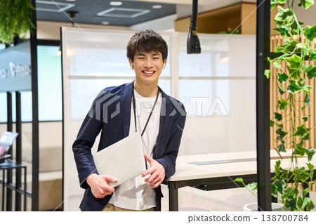 A Japanese system engineer works on his laptop near a potted plant in the office of a foreign-owned IT company. A Japanese system engineer works on his laptop near a potted plant in the office of a foreign-owned IT company. 138700784