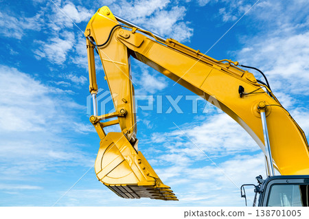 Yellow backhoe with hydraulic piston arm against blue sky. Heavy machine for excavation in construction site. Hydraulic machinery. Huge bulldozer. Heavy machine industry. Mechanical engineering. Yellow backhoe with hydraulic piston arm against blue sky. Heavy machine for excavation in construction site. Hydraulic machinery. Huge bulldozer. Heavy machine industry. Mechanical engineering. 138701005
