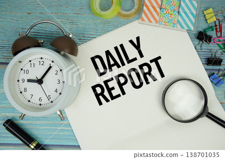 Daily Report text on a paper surrounded by office supplies, a magnifying glass, and a clock on a blue wooden surface 138701035
