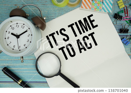 It's Time To Act text on a paper surrounded by office supplies, a magnifying glass, and a clock on a blue wooden surface It's Time To Act text on a paper surrounded by office supplies, a magnifying glass, and a clock on a blue wooden surface 138701040