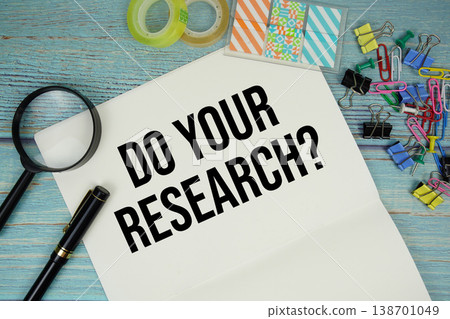 Do Your Research? text on a paper surrounded by office supplies and magnifying glass on a blue wooden surface Do Your Research? text on a paper surrounded by office supplies and magnifying glass on a blue wooden surface 138701049