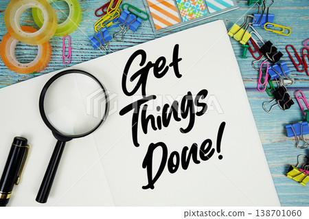 Get Things Done! text on a paper surrounded by office supplies and magnifying glass on a blue wooden surface Get Things Done! text on a paper surrounded by office supplies and magnifying glass on a blue wooden surface 138701060