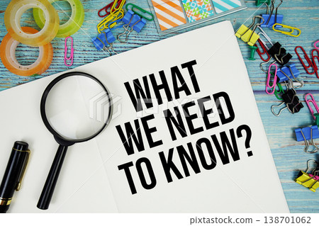 What We Need To Know? text on a paper surrounded by office supplies and magnifying glass on a blue wooden surface What We Need To Know? text on a paper surrounded by office supplies and magnifying glass on a blue wooden surface 138701062